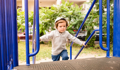 Determined serious toddler kid wearing hoodie having fun on a playground