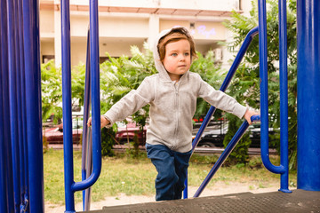 Obraz premium Determined serious toddler kid wearing hoodie having fun on a playground