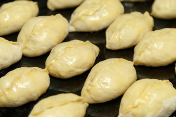 Cherry pies, cooked in the home kitchen, lie on the baking sheet.