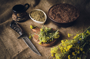 The rustic kitchen table is littered with herbs, seeds and spices. Ingredients for traditional national sauce. Soft focus.