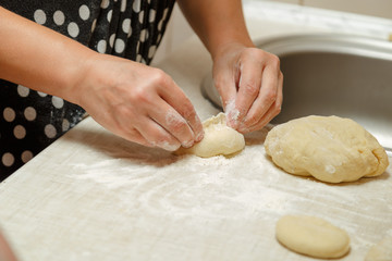 Cooking cherry pies in the home kitchen. Women's hands in the process of cooking cakes with cherries.