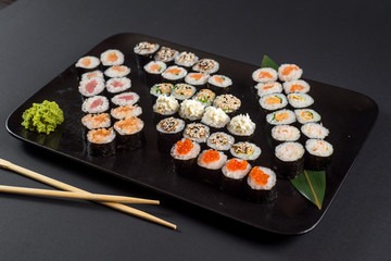 Japanese sushi rolls set served on black plate on dark background