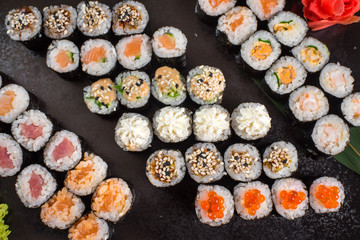 Japanese sushi rolls set served on black plate on dark background