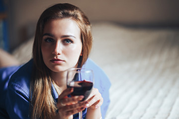 beautiful sad woman sitting on floor in shirt, hold wine she is upset, alone, nobody loved, without love
