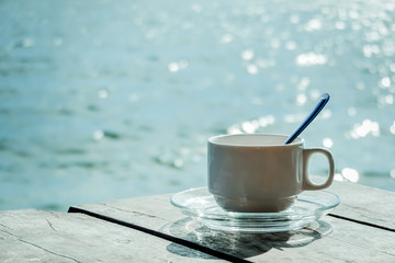 Aromatic coffee white cup in a blurry riverside view landscape background in sunshine