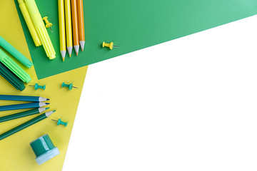 Top view knolling flat lay of workspace desk styled design school and office supplies with colored pencils on white, green and yellow background. Copy space.
