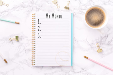 Festive golden stationary and coffee on white marble background. My Month wording. Copy space Top view. Horizontal