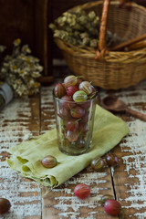 Fototapeta na wymiar Ripe gooseberries in a glass on a wooden background, garden berries