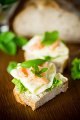 sandwich with cheese, salad leaves and red fish on a wooden