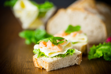 sandwich with cheese, salad leaves and red fish on a wooden