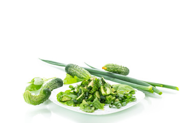fresh salad of cucumbers and greens in a plate isolated on white