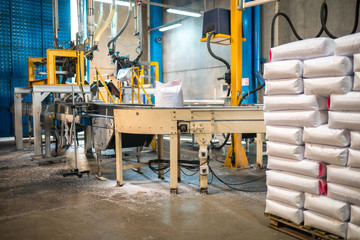 Rows or stacks of white sack bags at large warehouse in modern factory. Packaging on factory machine band or warehouse