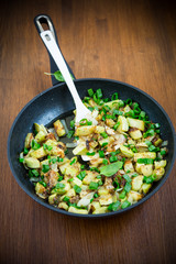 zucchini fried with onions and herbs in a pan on a wooden table