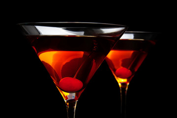 Closeup manhattan drinks with red cherry on black table