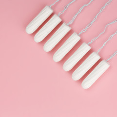 Medical female tampon on a pink background. Hygienic white tampon for women. Cotton swab. Menstruation, means of protection. Tampons on a red background.
