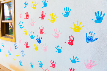 Colorful hand prints of hands isolated on white wall background. Children's handprints on school wall