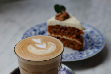 Cup of hot latte coffee with carrot cake as dessert with selective focus