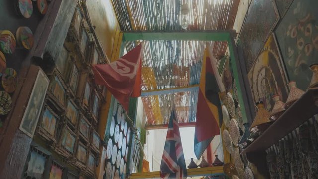Walking through an indoor market place in Morocco with bright colors flags paintings mirrors and many other objects for sale