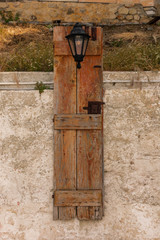 Black lantern on wooden panel in front of stone wall