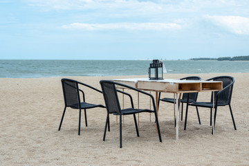 Fototapeta na wymiar Empty wooden table and chair on the beach for family dinner with blue sea.