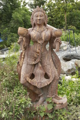 Fototapeta na wymiar Beautiful/perfect sculpture of Dancing devadasi Holding musical instrument on her hand carved from red sand stone with natural background.An female servant of god or jogini is a girl.
