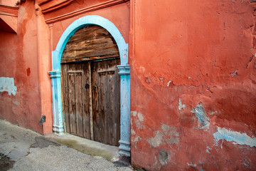 Historical village home's wooden door on red stone wall