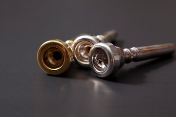 Three trumpet mouthpieces, gold and silver  against black background