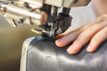 Sewing machine in a leather workshop in action with hands working with a leather details