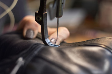 Sewing machine in a leather workshop in action with hands working with a leather details