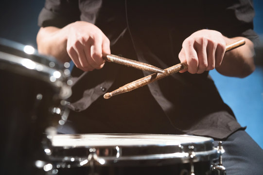 Close-up of a male drummer's hand holding drum sticks while sitting behind a drum set