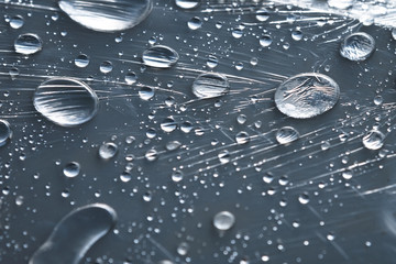 Close-up of raindrops of different sizes on the surface covered with cling film. Moisture weather and humidity concept