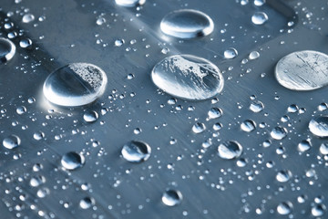 Close-up of raindrops of different sizes on the surface covered with cling film. Moisture weather...