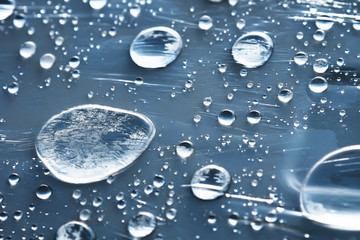 Close-up of raindrops of different sizes on the surface covered with cling film. Moisture weather and humidity concept