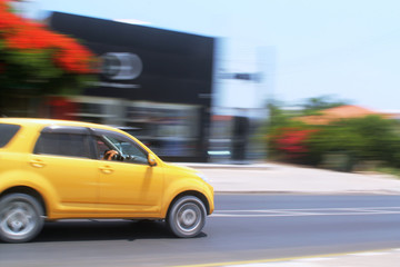 Fototapeta na wymiar Yellow car moving fast along the street