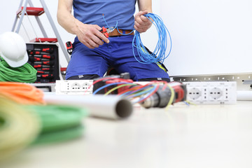 electrician at work with nippers in hand cut the electric cable, install electric circuits, electrical wiring