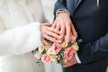 Obraz na płótnie Canvas Hands of the bride and groom on a bouquet