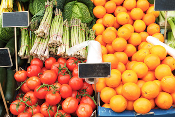 counter at the farmer’s street market with corn cobs and spruce branches in wooden boxes with black chalk boards for prices