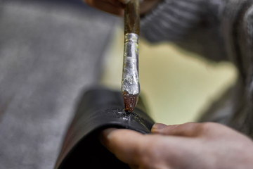 Tailor's hands is workin with glue and leather detail for bags .