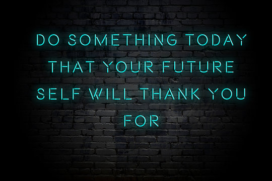 Neon inscription of positive wise motivational quote against brick wall 