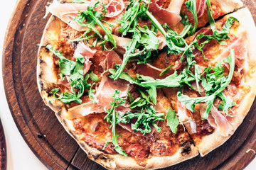 pizza with ham, mozzarella, tomato sauce from the oven on wooden plate in restaurant of Catania, Sicily, Italy.