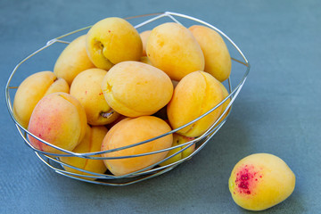 Delicious ripe apricots in a metal bowl on the table close-up. Horizontal top view.