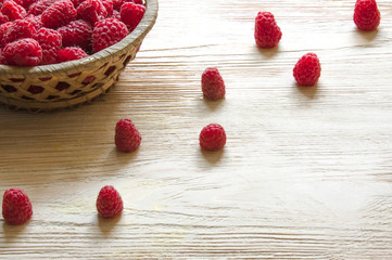 raspberries in a basket on a light wooden background