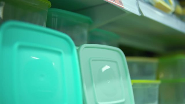 Point of view on shelf with colorful reusable food containers in supermarket.Camera moves along the rack with lunch boxes, close-up.