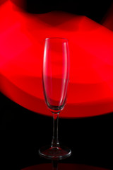 A single wine glass isolated on a black background with red white pink and orange neon light painting streaks of light behind them. Light wave, game of colors, drawing light
