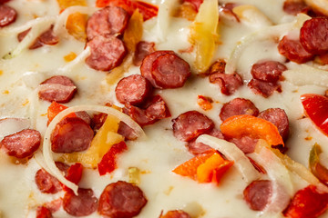 Top view of hot pizza with chili pepper , hot sausages, onion, tomatoes and cheese.