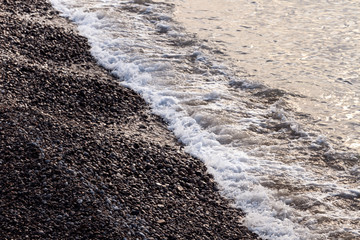 sea waves with pebbles and foam