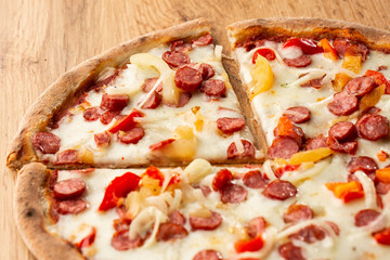 Top view of hot pizza with chili pepper , hot sausages, onion, tomatoes and cheese. 