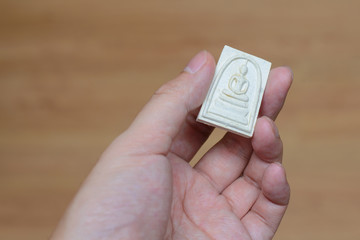 Hand holds Thai amulet isolated on background