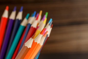 Pens and pencils in metal holder in front of wall background