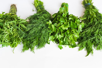 Different bunches of organic greens/herb: arugula, parsley, dill isolated on white background